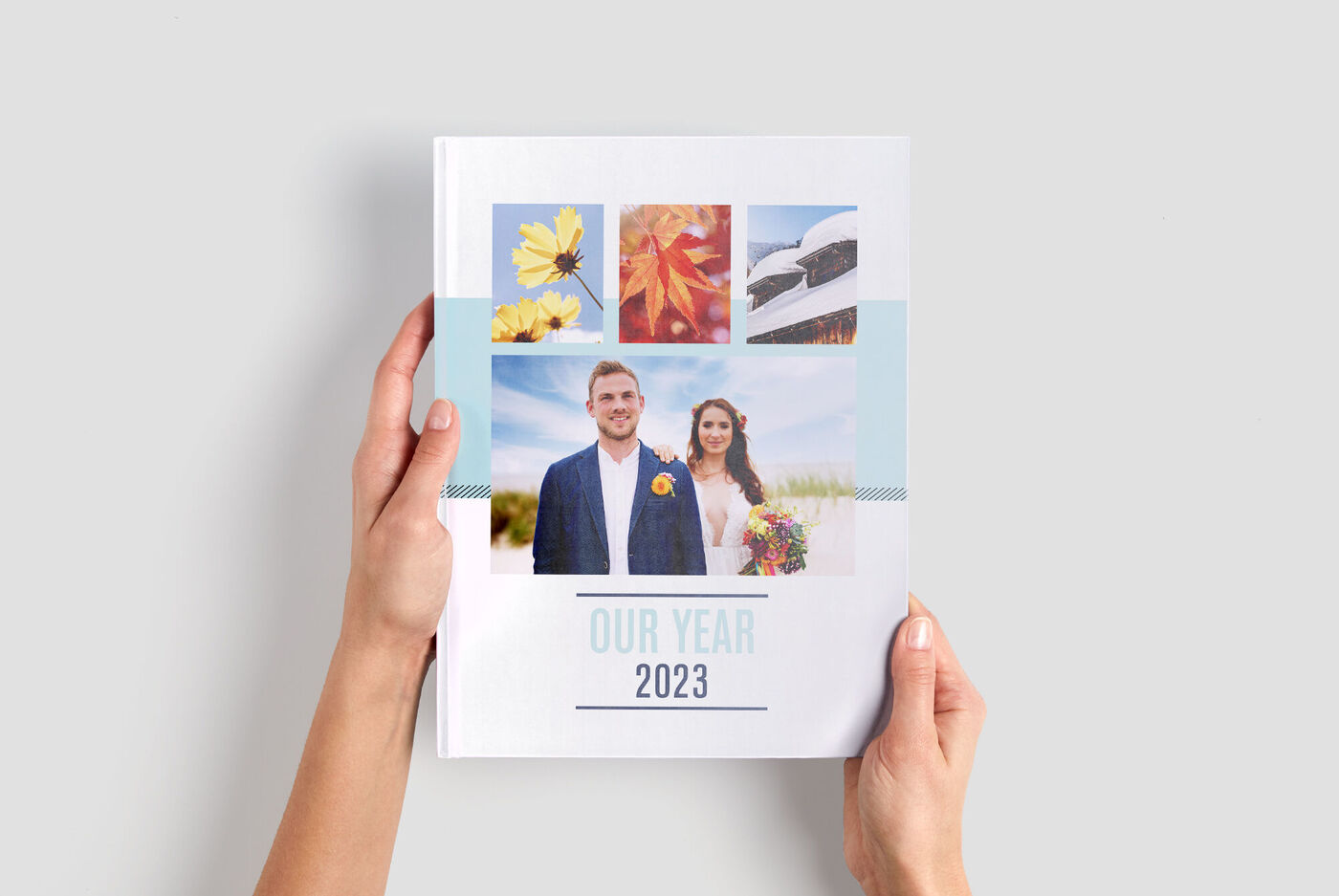 Iemand houdt een CEWE fotoboek vast met kleurrijke foto's en een jaarthema.