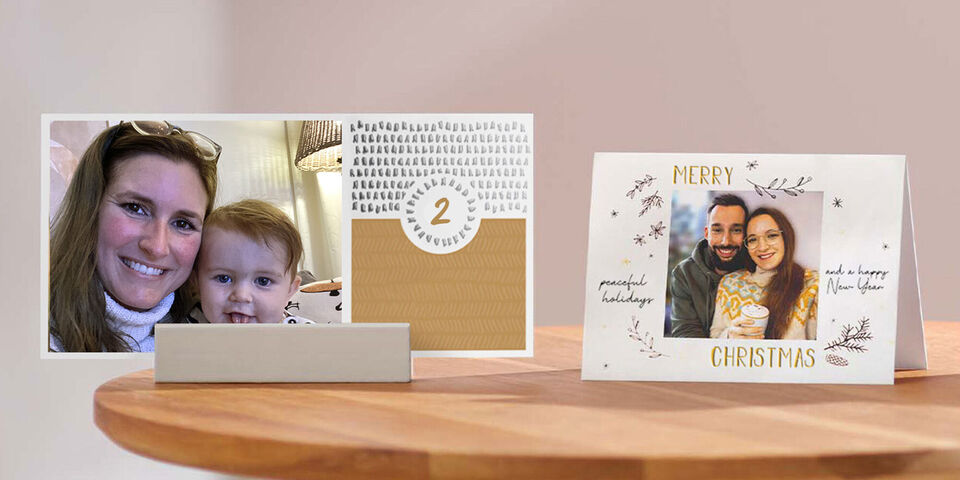 Twee liefdevol ontworpen CEWE wenskaarten op een tafel. Een kaart toont een kerstboodschap, de andere een familiefoto.